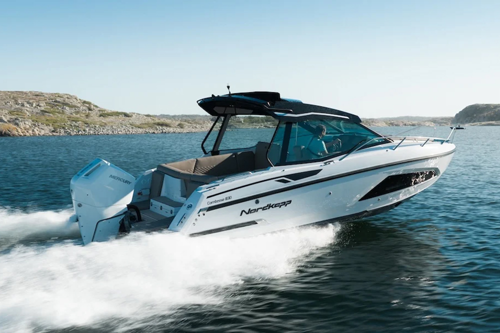 Nordkapp Comtesse 830 sunroof weekend cruiser with a single Mercury outboard running at speed past a rocky coastline