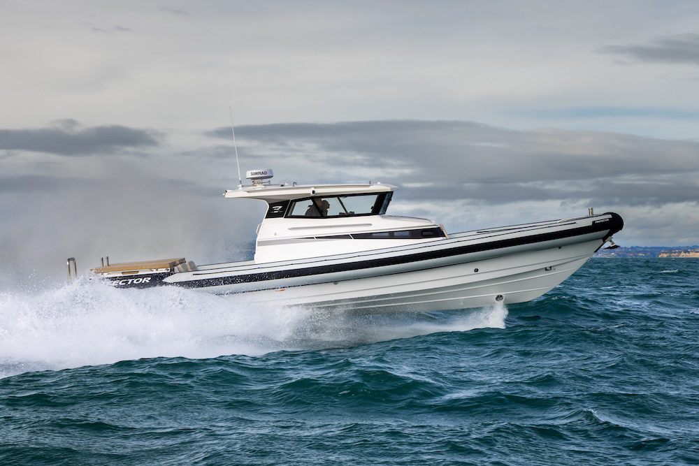 A Protector RIB chase boat cuts through choppy water at speed, throwing spray under overcast skies.