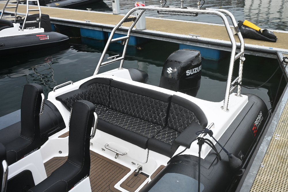 Redbay SF750 four-person rear bench in diamond-pattern upholstery, with Suzuki outboard and A-frame behind