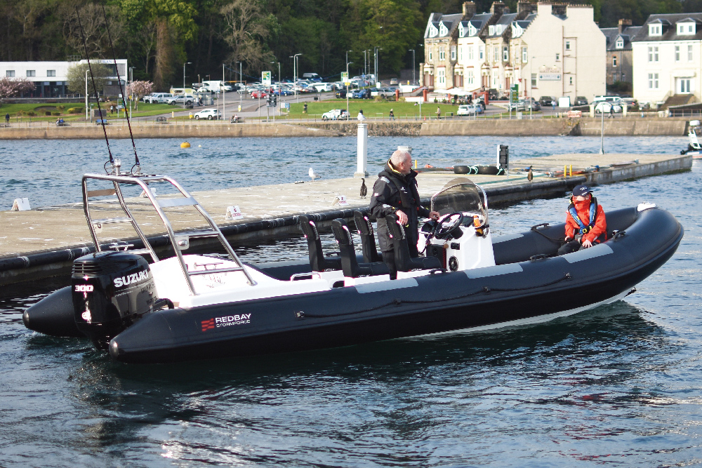 Redbay SF750 with black tubes and single Suzuki outboard manoeuvring off a pontoon in Oban